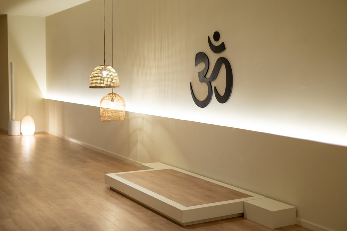Serene yoga studio featuring om symbol on wall, warm lighting, and a low meditation platform, creating a calm atmosphere